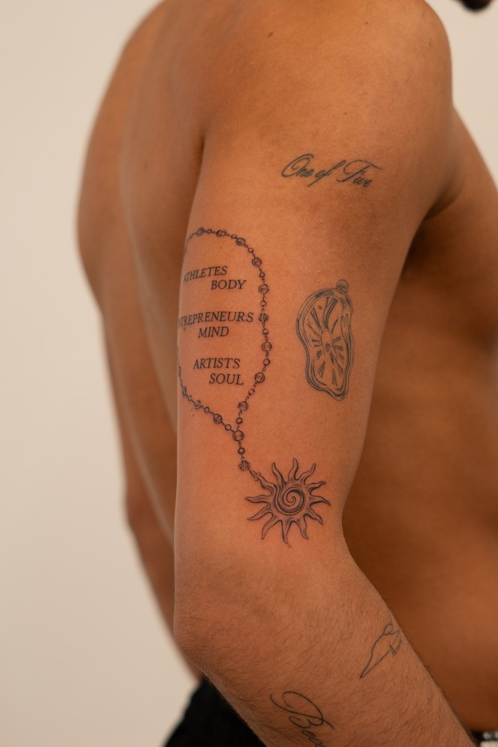 Sun and lettering tattoo on upper arm