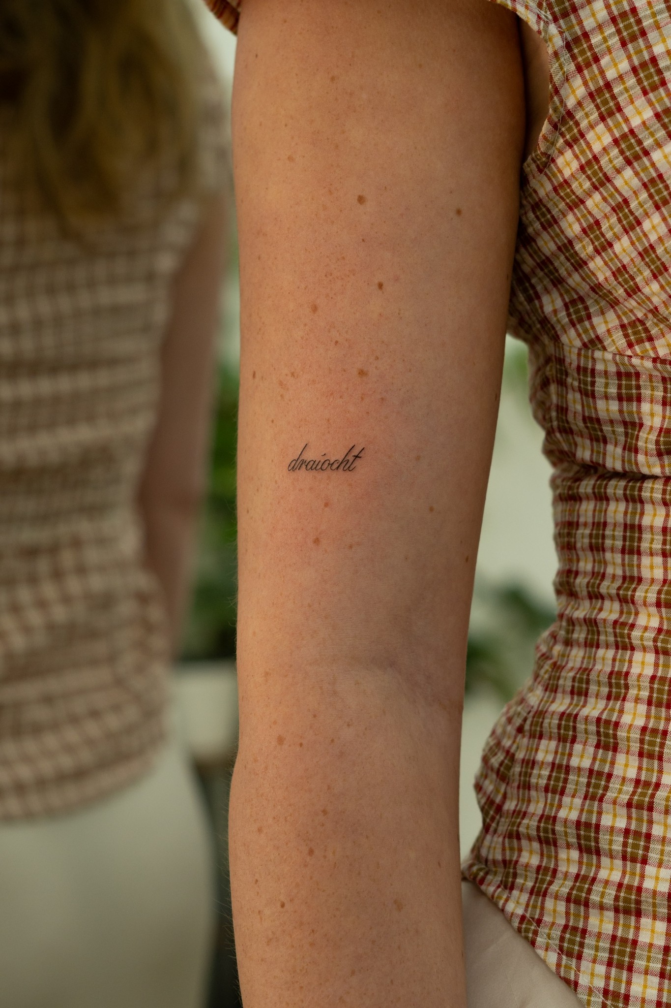 Cursive word tattoo on upper arm